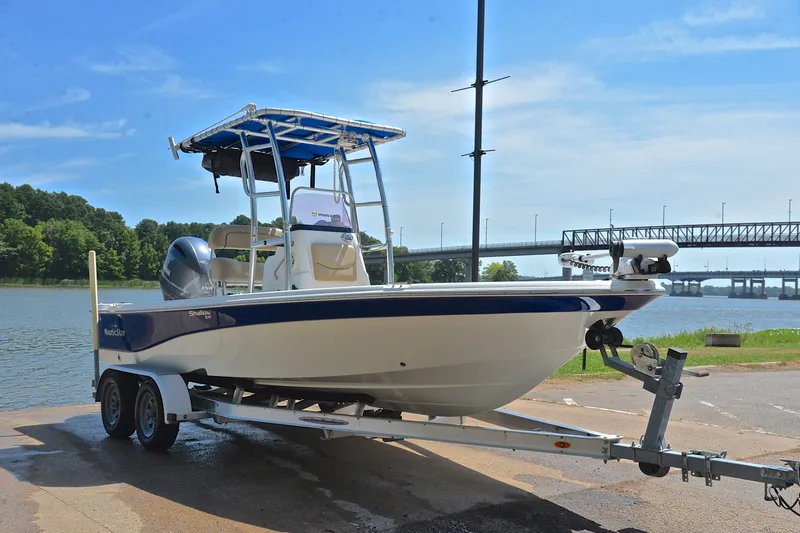 Slide: The Image of 2019 NauticStar 215 XTS Shallow Bay boat on trailer by a scenic river. - 16