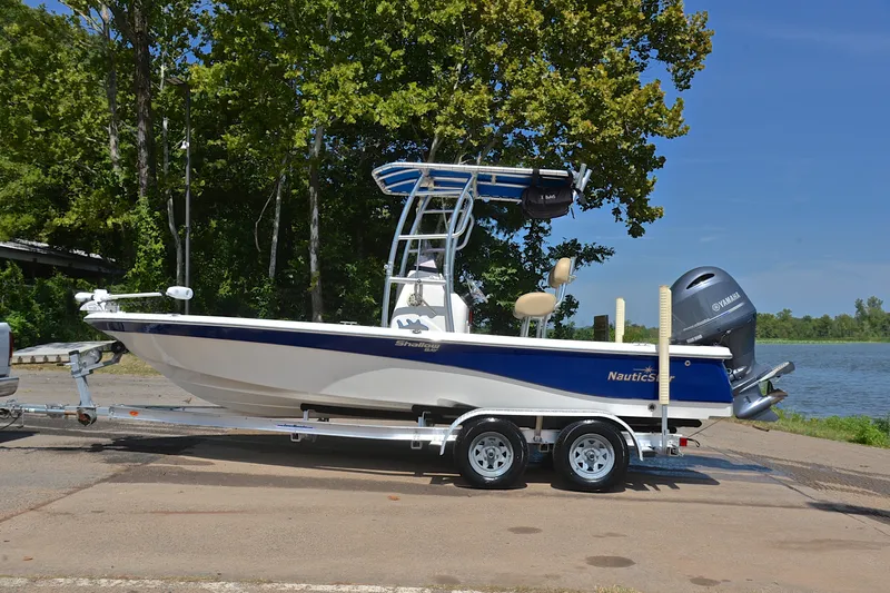 Slide: The Image of 2019 NauticStar 215 XTS Shallow Bay boat on trailer by a lake. - 11
