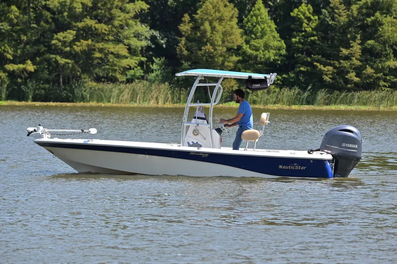 Slide: The Image of 2019 NauticStar 215 XTS Shallow Bay boat cruising on a serene lake. - 9