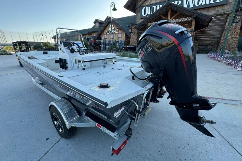 Slide: The Image of 2024 Ranger RB190 Bay boat with powerful outboard motor, parked outside a rustic building. - 7