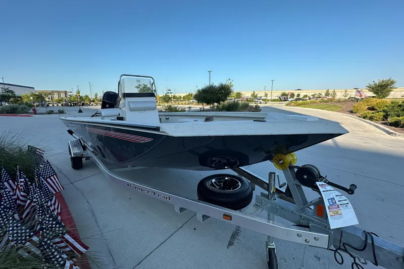 Slide: The Image of 2024 Ranger RB190 Bay boat on trailer, displayed outdoors with American flags nearby. - 4