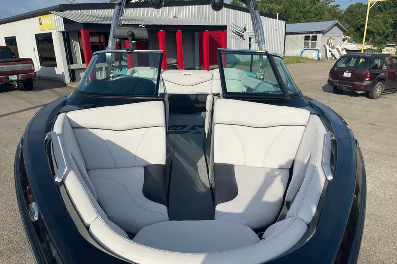 Slide: The Image of 2018 MasterCraft XT23 boat with white interior, parked outdoors near buildings. - 6