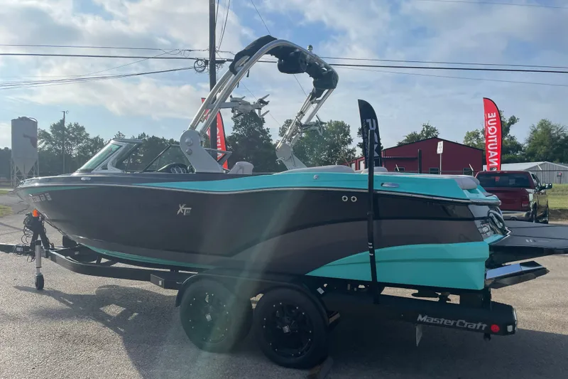 Slide: The Image of 2018 MasterCraft XT23 boat on trailer, turquoise and black design, parked outdoors. - 3
