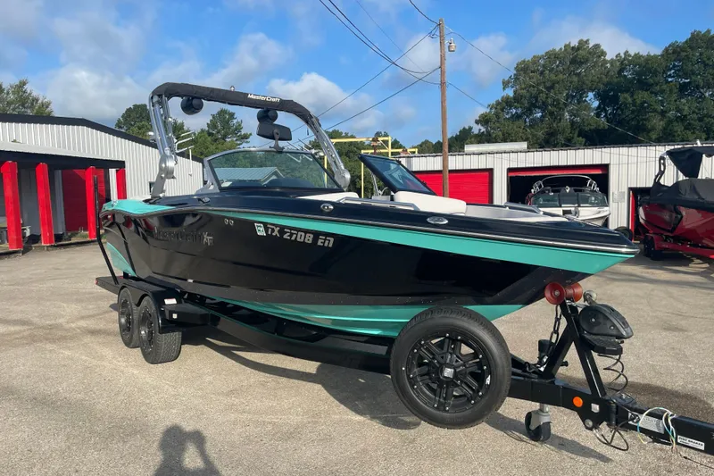 Slide: The Image of 2018 MasterCraft XT23 boat on trailer, parked outdoors near storage units. - 5