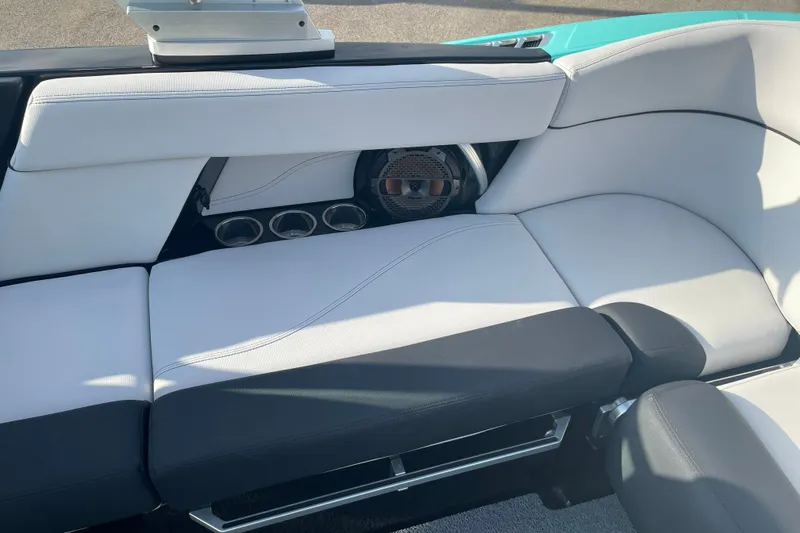 Slide: The Image of 2018 MasterCraft XT23 boat interior with white and black seating, cup holders, and speaker. - 15