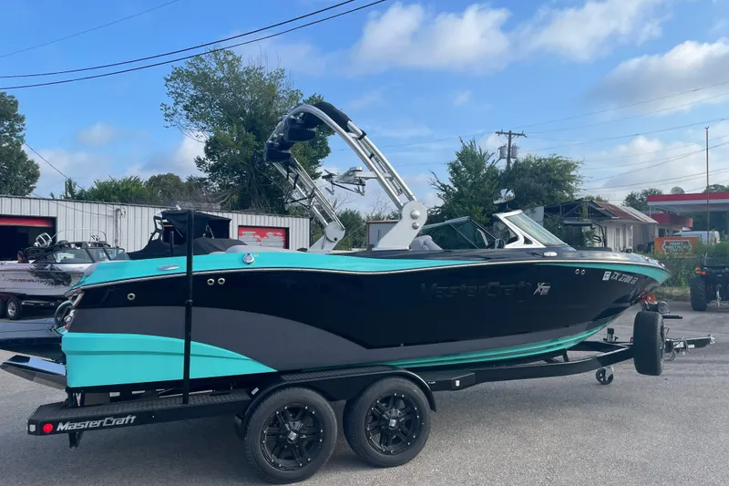 The Image of 2018 MasterCraft XT23 boat on trailer, featuring sleek black and turquoise design. - 1