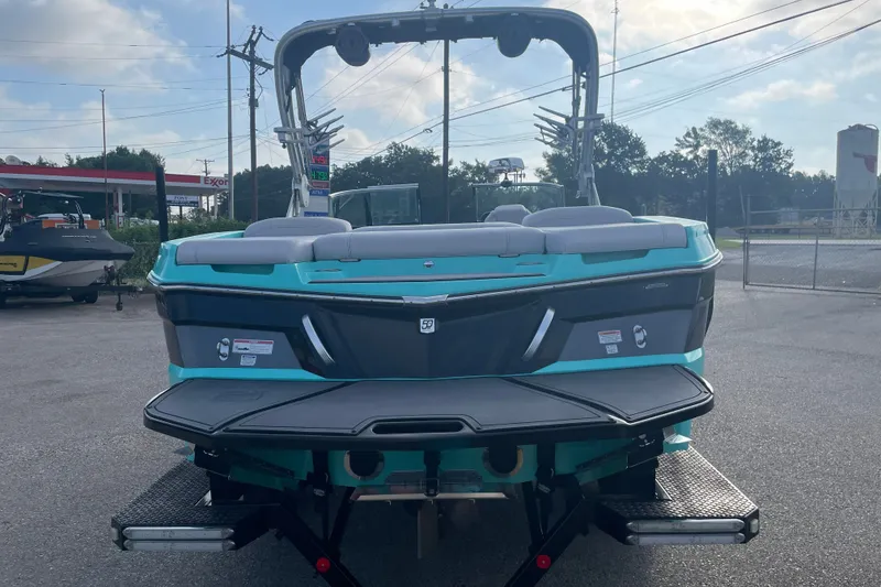 Slide: The Image of 2018 MasterCraft XT23 boat in a parking lot, rear view with teal and black design. - 2