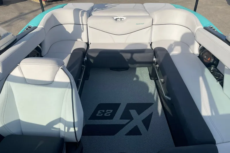 Slide: The Image of 2018 MasterCraft XT23 boat interior with gray seating and logo on carpet. - 11