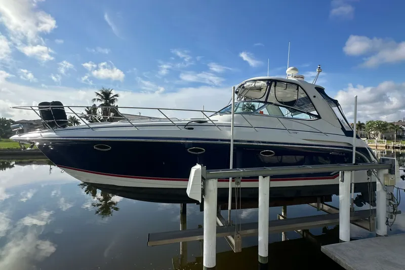 The Image of 2008 Formula 37 Performance Cruiser on lift, reflecting on calm water under blue sky. - 0