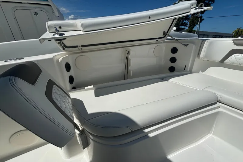Slide: The Image of 2021 World Cat 295 CC boat interior with white cushioned seating and storage compartment. - 28