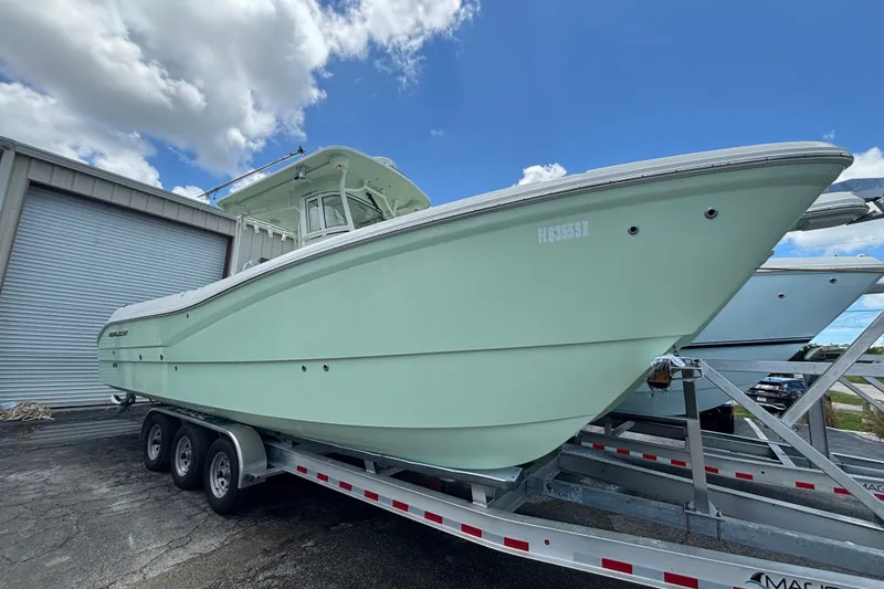 Slide: The Image of 2021 World Cat 295 CC boat on trailer, parked outdoors under blue sky. - 1