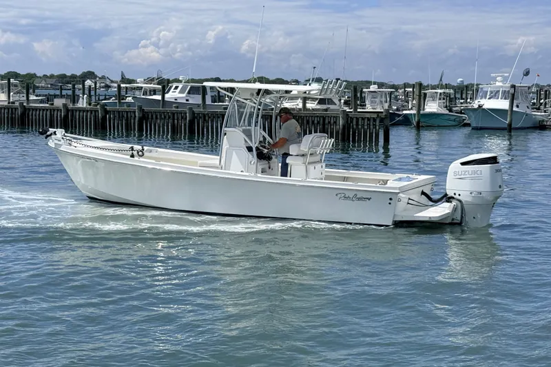 Slide: The Image of 2023 Pair Customs 24 Center Console DV boat cruising in a marina with Suzuki outboard. - 1