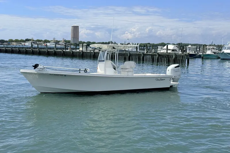 Slide: The Image of 2023 Pair Customs 24 Center Console DV boat on calm water near a marina. - 2