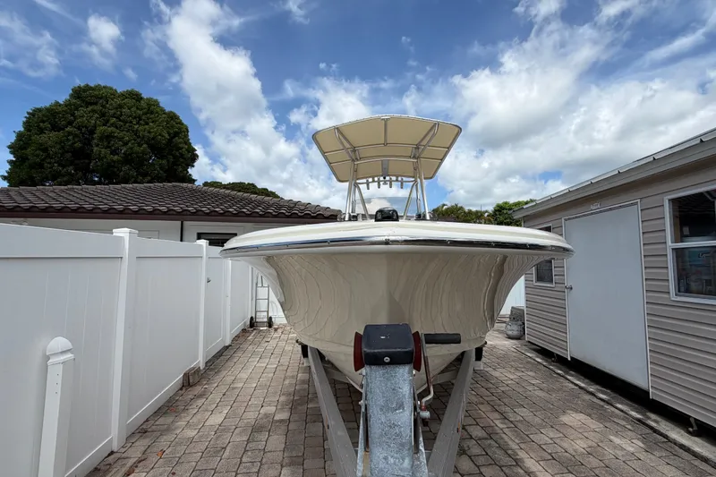 Slide: The Image of 2017 Scout 195 Sportfish boat on trailer, parked between buildings under a cloudy sky. - 2