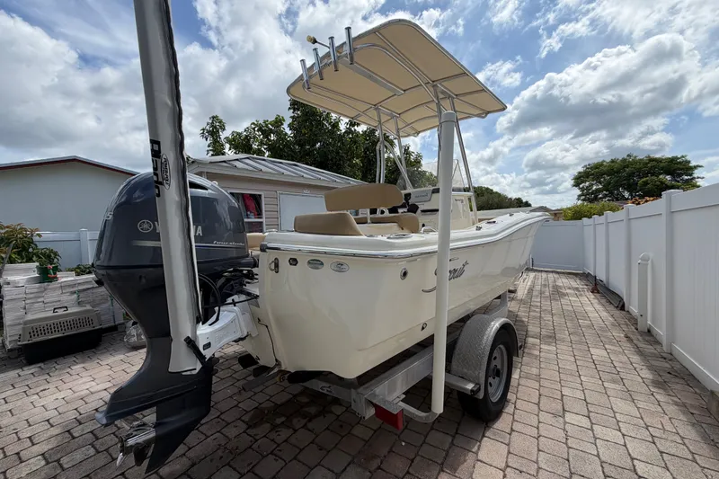 Slide: The Image of 2017 Scout 195 Sportfish boat on trailer, parked in driveway under cloudy sky. - 5
