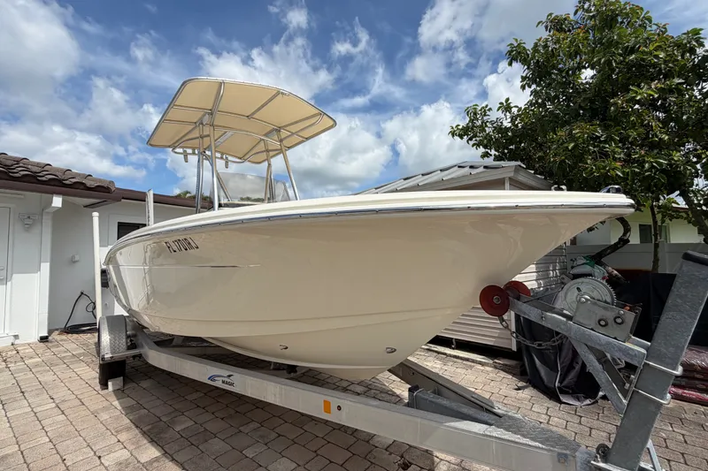 Slide: The Image of 2017 Scout 195 Sportfish boat on trailer, parked in driveway under blue sky. - 4