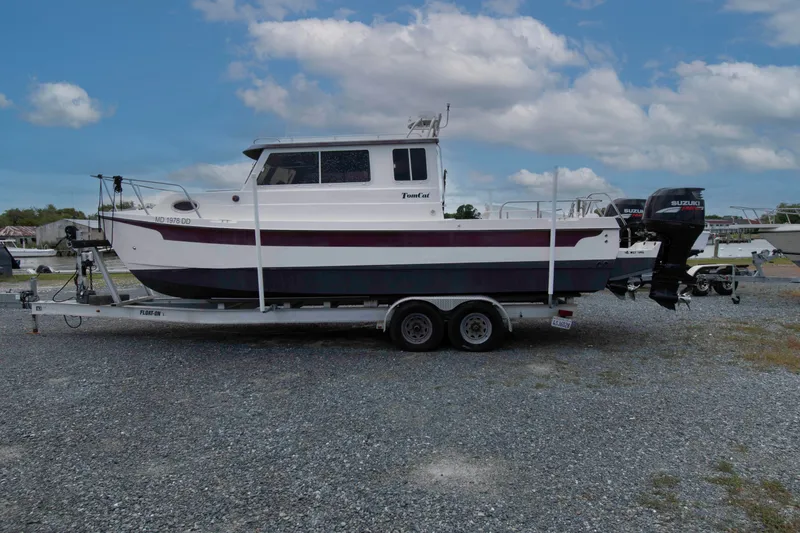 Slide: The Image of 2007 C-Dory 25' Tomcat Catamaran on trailer, parked on gravel lot under cloudy sky. - 2
