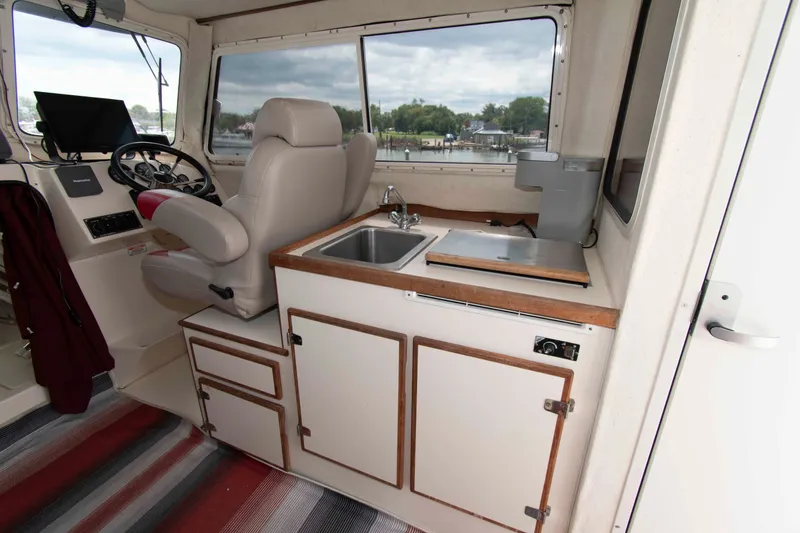 Slide: The Image of 2007 C-Dory 25' Tomcat Catamaran interior with helm, sink, and storage cabinets. - 16