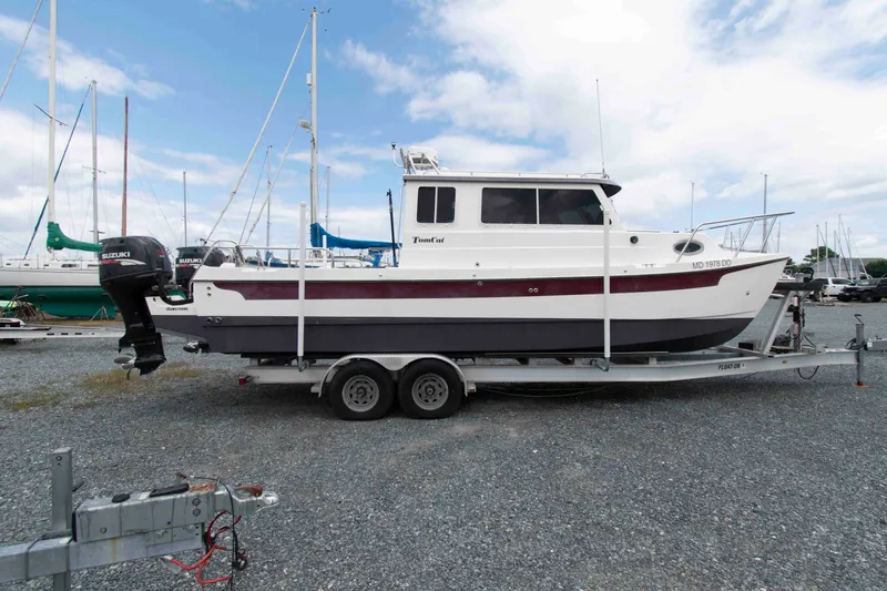 Slide: The Image of 2007 C-Dory 25' Tomcat Catamaran on trailer, parked in a marina with sailboats. - 3