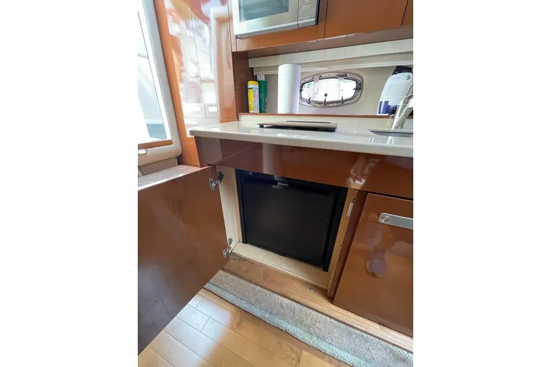 Slide: The Image of 2012 Sea Ray Sundancer 310 yacht interior kitchen with open cabinet and mini fridge. - 11