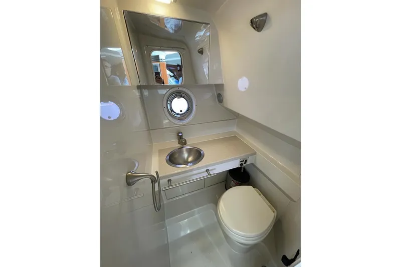 Slide: The Image of 2012 Sea Ray Sundancer 310 bathroom with sink, toilet, and porthole window. - 13