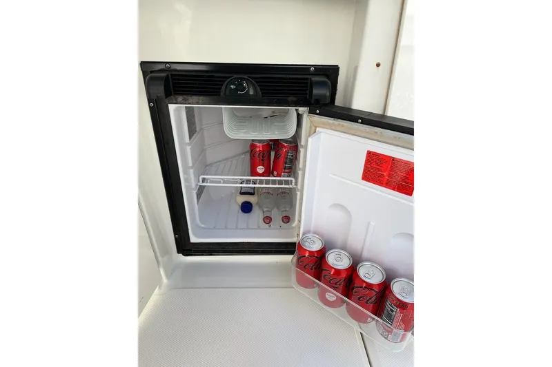 Slide: The Image of Mini fridge on 2012 Sea Ray Sundancer 310, stocked with Coca-Cola cans and condiments. - 7
