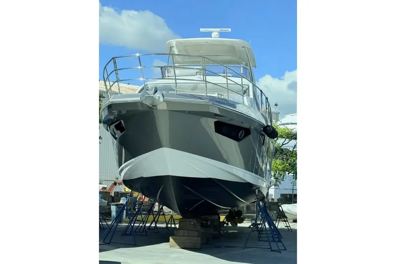 Slide: The Image of 2018 Azimut 66 Flybridge yacht on stands, viewed from the front under a clear blue sky. - 48
