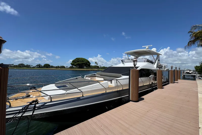 Slide: The Image of 2018 Azimut 66 Flybridge yacht docked by a scenic waterfront under a clear blue sky. - 3