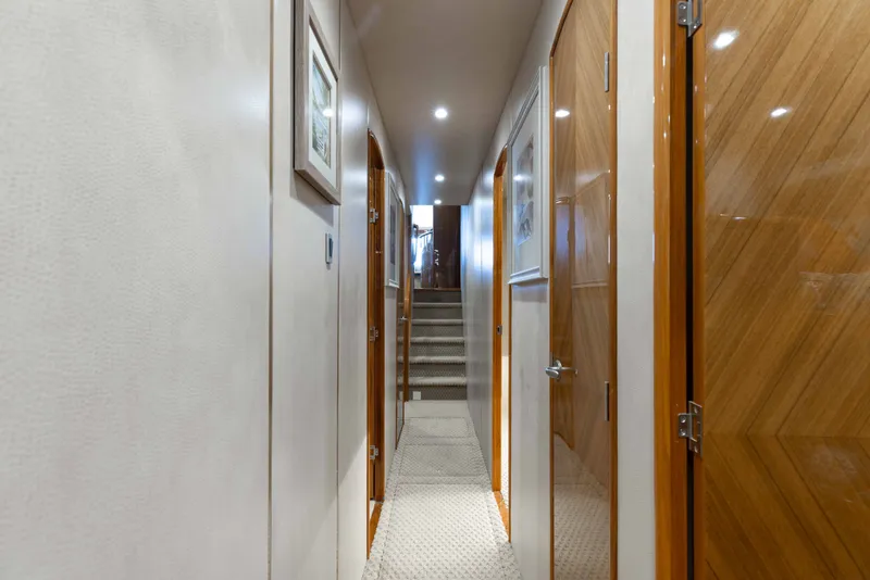 Slide: The Image of Hallway inside 2012 Viking 76 Enclosed Bridge yacht, featuring wooden doors and carpeted stairs. - 81