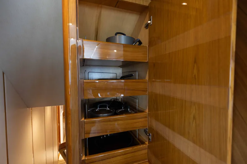 Slide: The Image of Wooden cabinet with open drawers, showcasing cookware on a 2012 Viking 76 Enclosed Bridge yacht. - 79