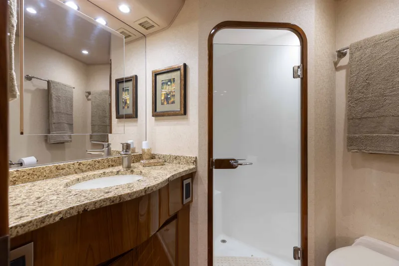 Slide: The Image of Luxurious bathroom in 2012 Viking 76 Enclosed Bridge yacht with granite countertop and glass shower door. - 93