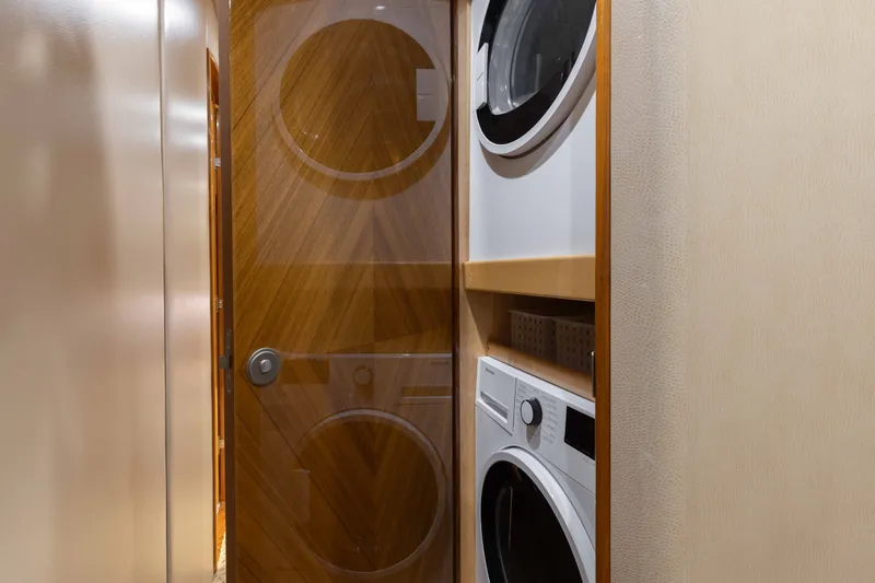 Slide: The Image of Laundry area inside 2012 Viking 76 Enclosed Bridge yacht with stacked washer and dryer. - 99