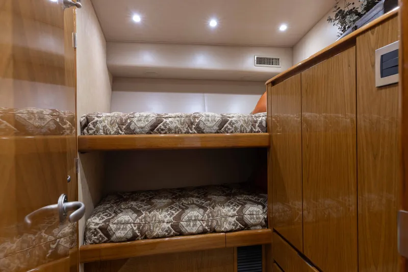 Slide: The Image of Bunk beds in 2012 Viking 76 Enclosed Bridge yacht cabin with wooden cabinetry. - 98