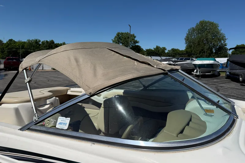 Slide: The Image of 2000 Sea Ray 180 Bow Rider with beige canopy in a marina setting. - 19