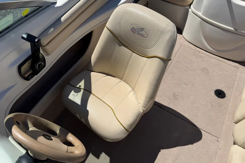 Slide: The Image of Interior of a 2000 Sea Ray 180 Bow Rider boat, featuring beige seating and steering wheel. - 13