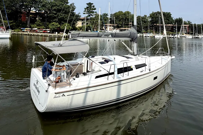 Slide: The Image of 2021 Hanse 348 sailboat cruising on a calm lake with lush greenery. - 2