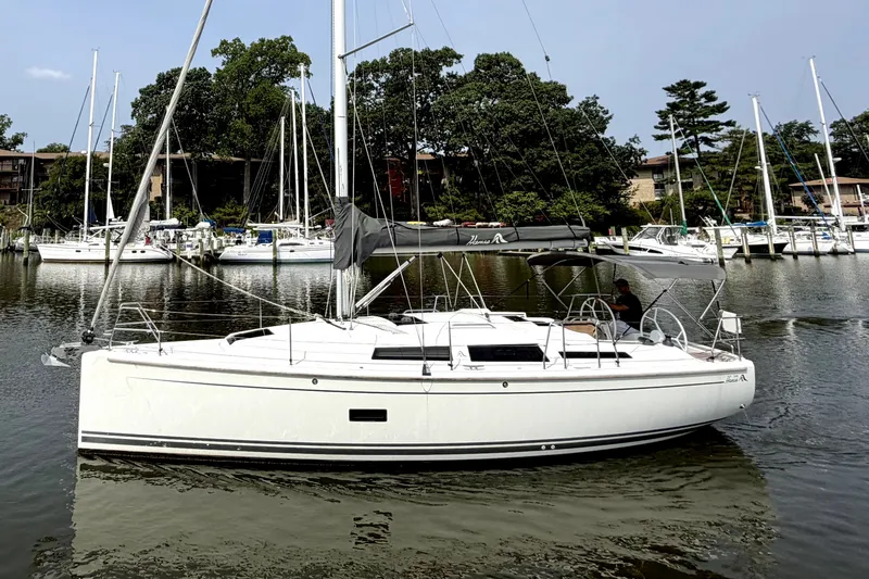 Slide: The Image of 2021 Hanse 348 sailboat docked in a marina with surrounding trees and boats. - 5