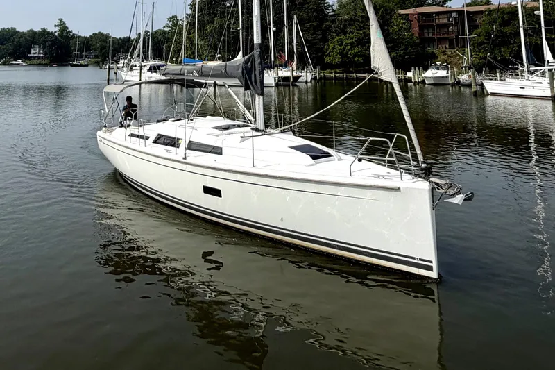 Slide: The Image of 2021 Hanse 348 sailboat cruising on a calm lake with surrounding greenery. - 1