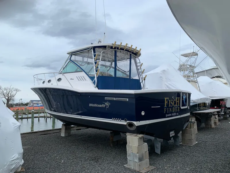 Slide: The Image of A 2004 Wellcraft 330 Coastal boat is on blocks. It features a blue hull design. - 27
