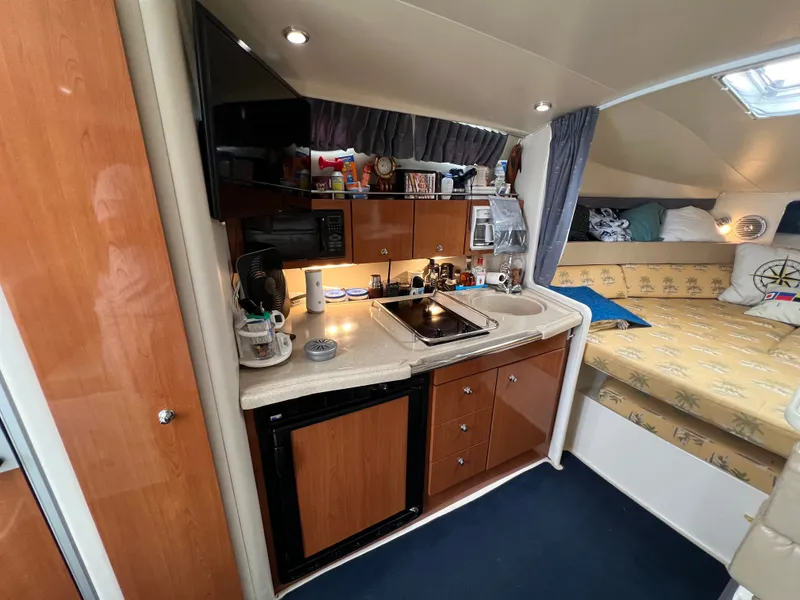 Slide: The Image of The interior of a 2004 Wellcraft 330 Coastal features a compact kitchen with sink, stove, and fridge. - 9