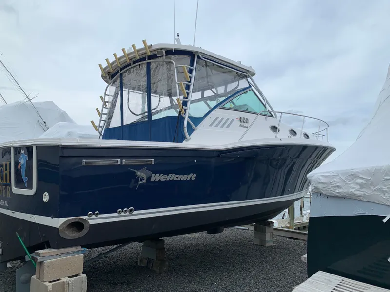 Slide: The Image of A 2004 Wellcraft 330 Coastal boat is on blocks. It features a blue hull design. - 28