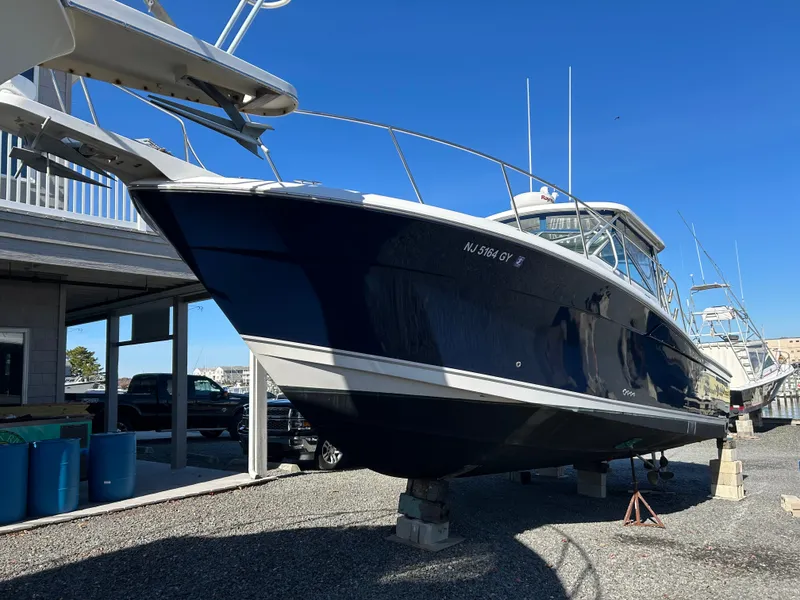 Slide: The Image of A 2004 Wellcraft 330 Coastal on a dry dock. It features a dark blue hull. - 29