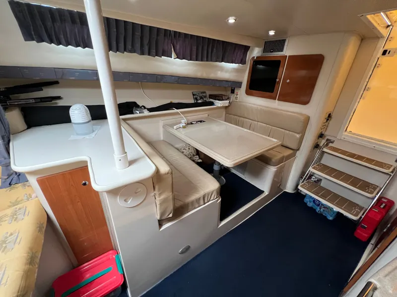 Slide: The Image of The interior of a 2004 Wellcraft 330 Coastal features a cozy seating area with a table and kitchenette. - 11