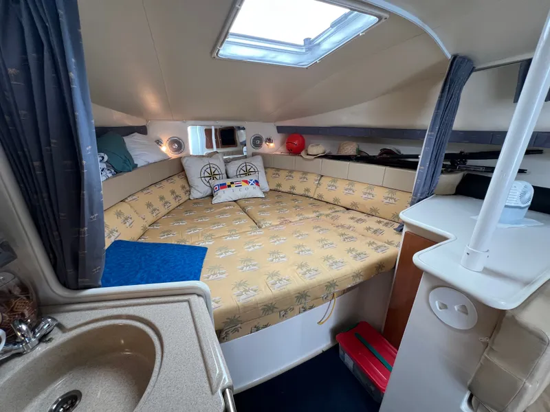 Slide: The Image of The cabin of the 2004 Wellcraft 330 Coastal features a cozy bed with nautical-themed pillows. - 8