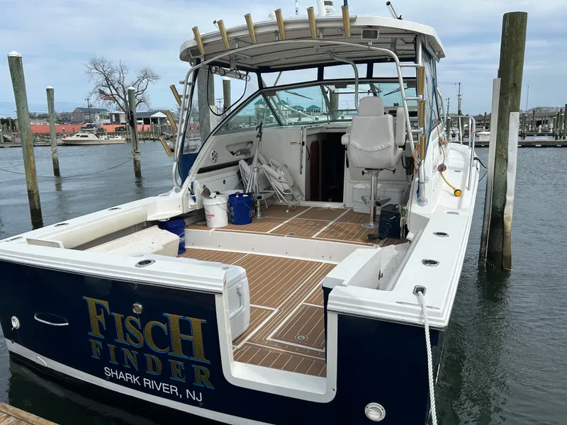Slide: The Image of A 2004 Wellcraft 330 Coastal boat docked. It features an open cabin and fishing rod holders. - 3