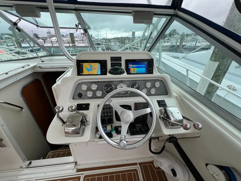 Slide: The Image of The cockpit of a 2004 Wellcraft 330 Coastal with modern instruments and a white steering wheel. - 6