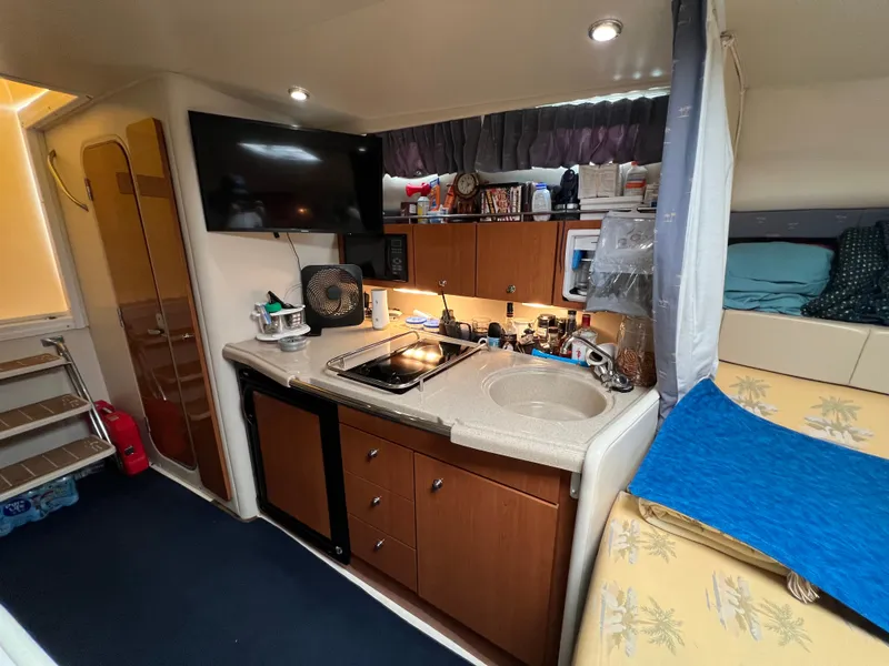 Slide: The Image of The cabin of a 2004 Wellcraft 330 Coastal features a compact kitchen with a sink and stove. - 10