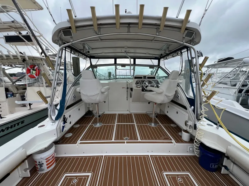 Slide: The Image of The image shows the cockpit of a 2004 Wellcraft 330 Coastal with two white seats and rod holders. - 5