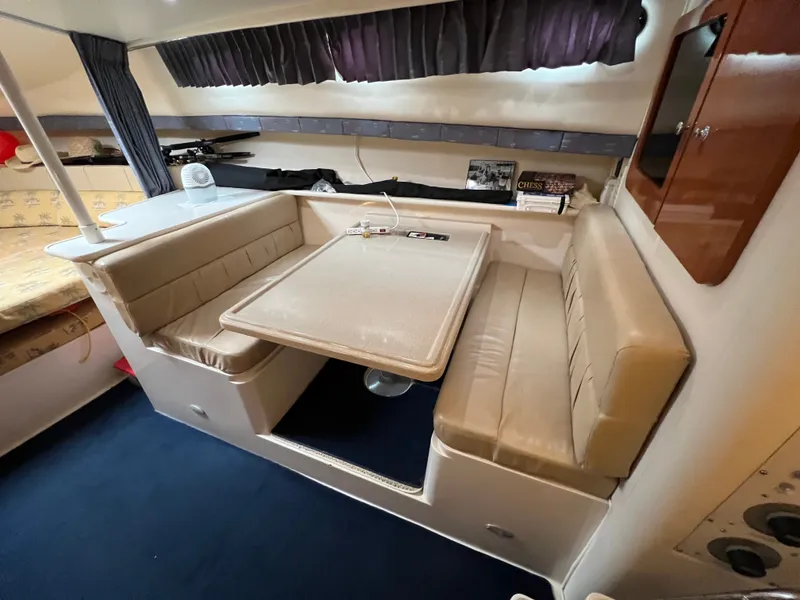 Slide: The Image of The 2004 Wellcraft 330 Coastal cabin features a cozy seating area with a table and cushioned benches. - 12