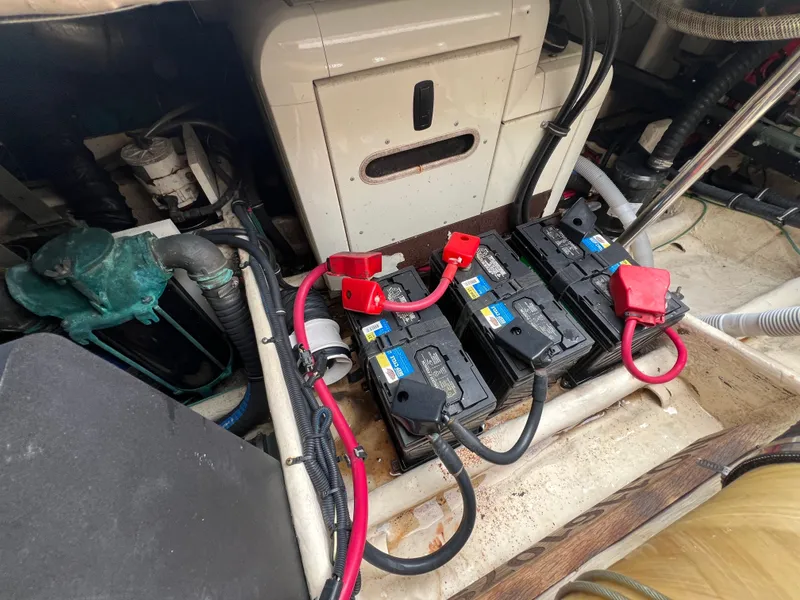 Slide: The Image of The engine compartment of a 2004 Wellcraft 330 Coastal shows multiple batteries and cables. - 24